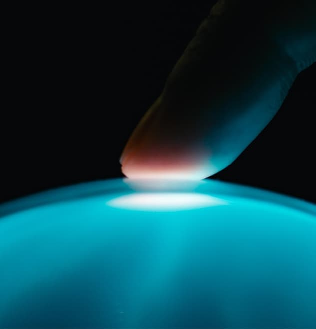 Human finger touching a blue light orb surface