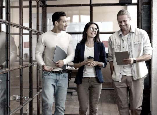 Happy employees collaborating as they walk down the hallway